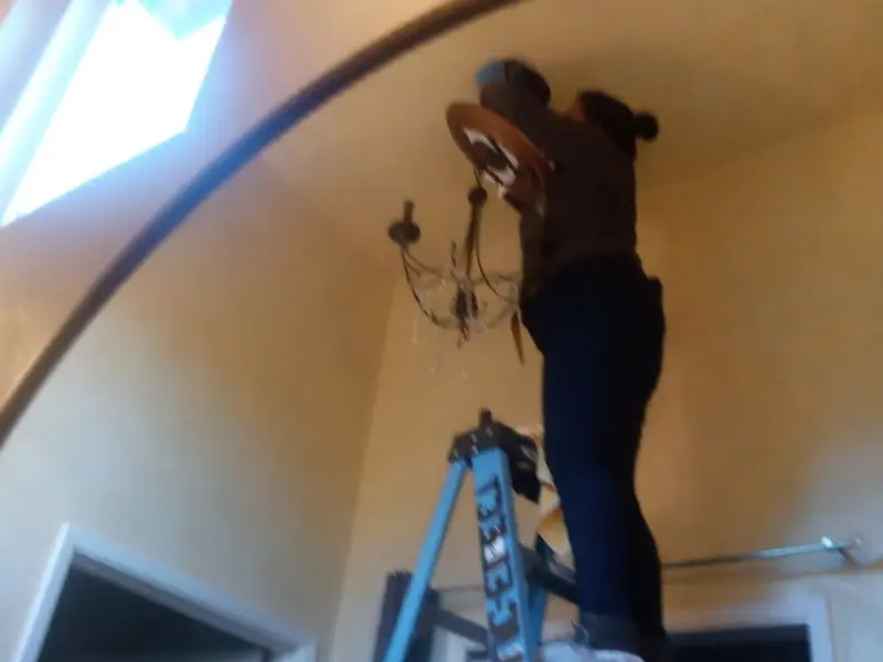 Electrician installing a chandelier in a Rendon residence